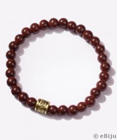 Brăţară din perle de sticlă maro, cu element decorativ auriu, metalizat, pe fir elastic.